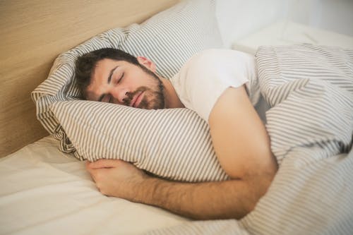 Man sleeping in bed hugging his pillow