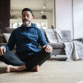Mature man meditating on the floor at home
