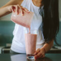 Woman at her kitchen counter pouring a smoothie from a blender into a glass