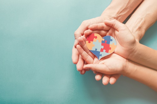 Adult and child hands together holding a puzzle in their palms