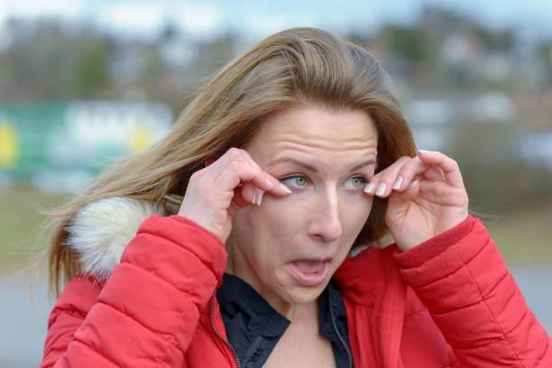 Young woman rubbing her eyes on a cold windy day