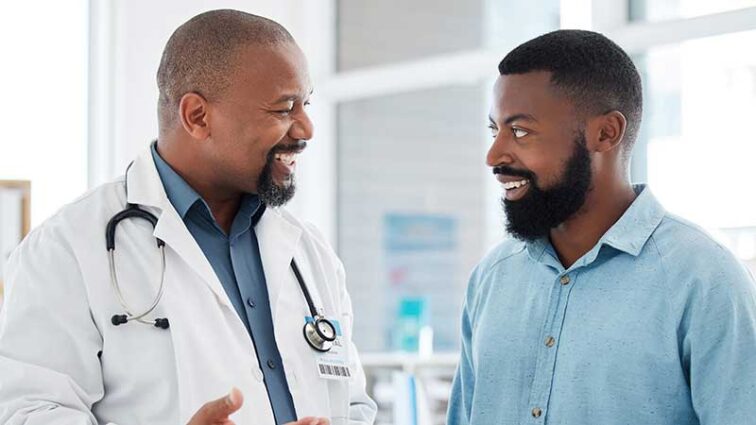 Smiling male physician talking to a smiling male patient