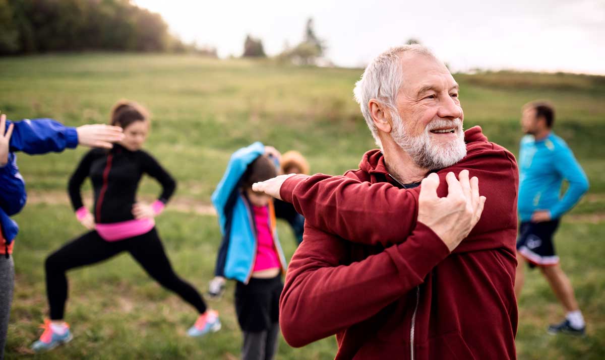 Mixed age active group of people stretching in a park