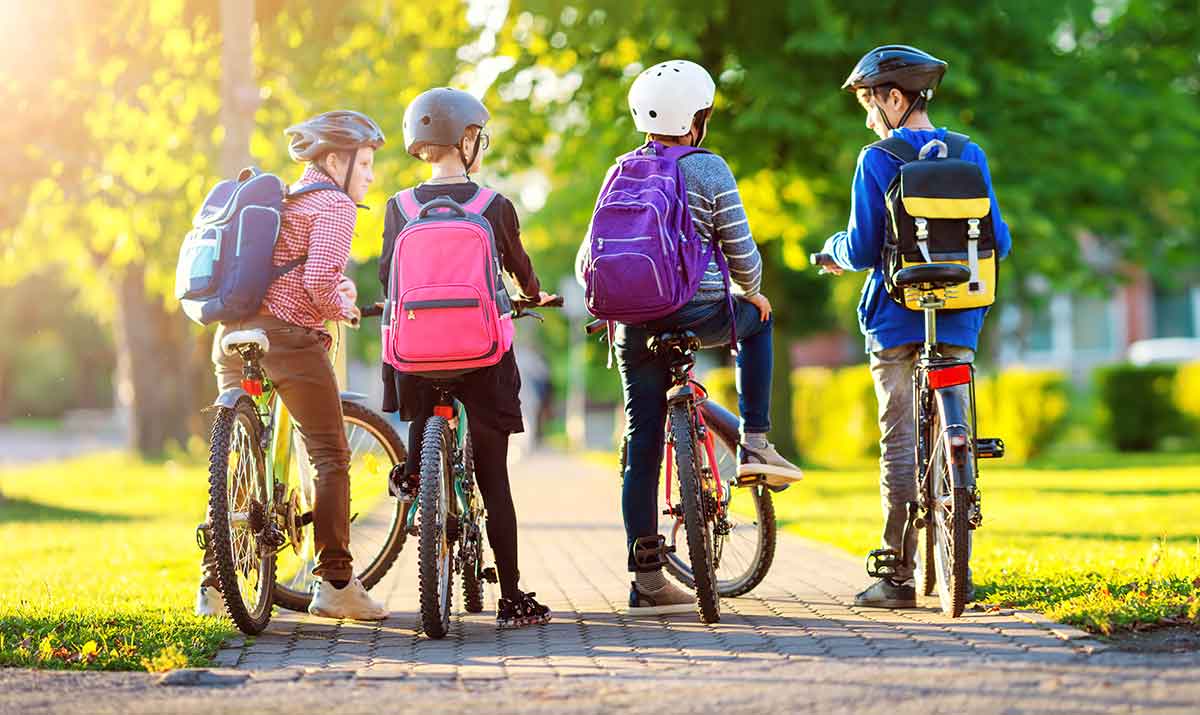 Grade school kids with backpacks riding bikes
