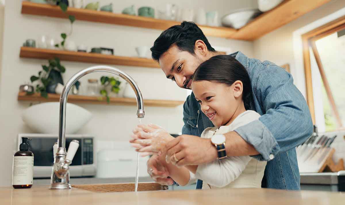 Father and daughter practicing the healthy habit of washing hands in the kitchen
